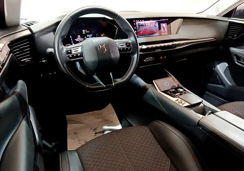 Intérieur du DS4 E-TENSE 2023 vu côté conducteur, volant cuir, tableau de bord numérique et écran tactile central.