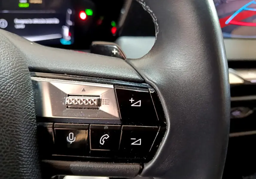 Gros plan sur les commandes du volant cuir noir du DS4 E-TENSE 225 TROCADERO, boutons multifonctions visibles.