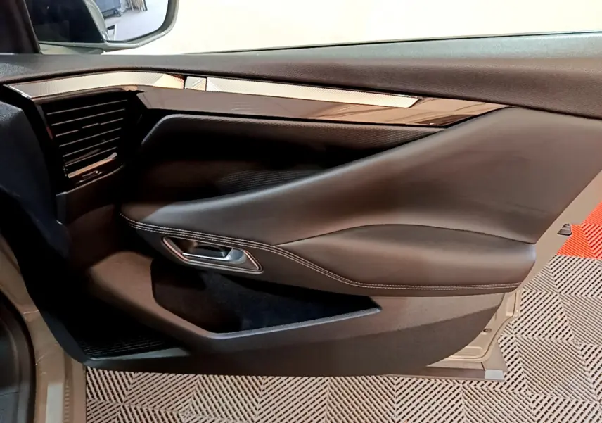Gros plan sur la porte côté gauche du DS4 E-TENSE 225 TROCADERO gris foncé, avec garniture cuir et insert brillant.