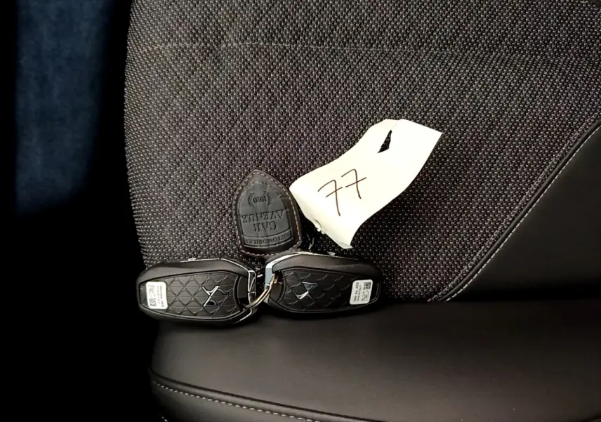 Gros plan sur les clés noires DS posées sur un siège tissu gris foncé et cuir noir du DS4 E-TENSE 2023.