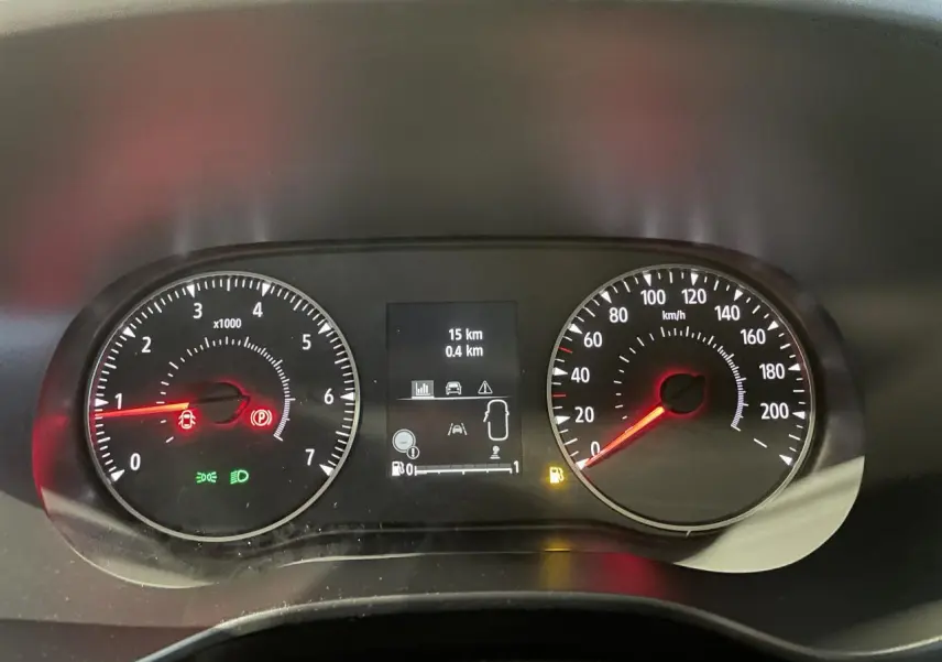 Tableau de bord du Dacia Sandero 2025 avec compte-tours, compteur de vitesse et écran central affichant 15 km et alertes.