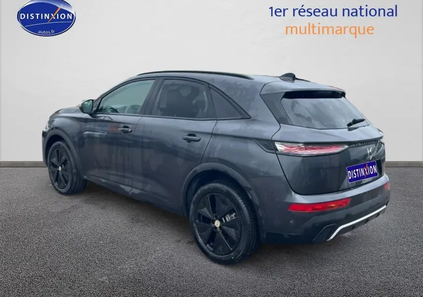 Vue 3/4 arrière droite d'un DS7 gris titane avec jantes noires et feux arrière LED allumés.