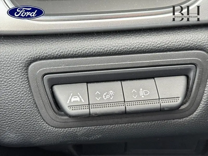 Boutons de réglage des aides à la conduite sur tableau de bord noir, avec commandes de maintien de trajectoire et éclairage.