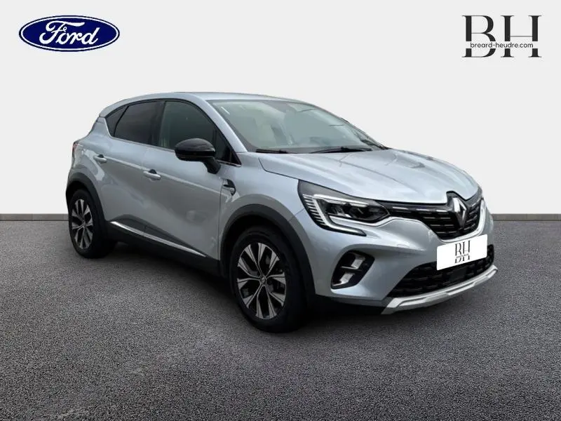 Renault Captur 1.6 E-Tech hybride gris Highland en 3/4 avant droit avec jantes alliage et détails noirs contrastants.