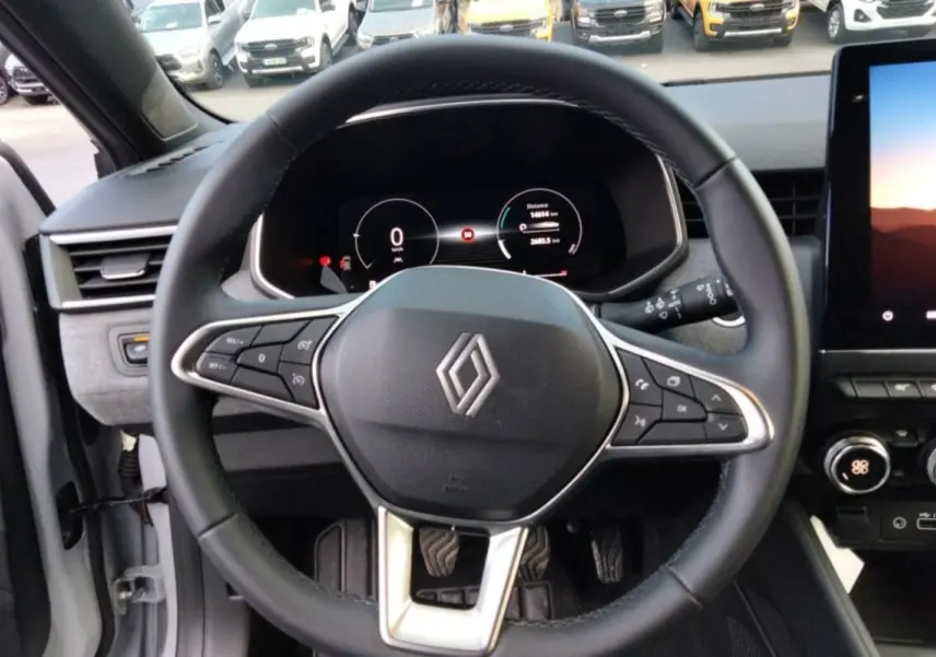 Vue intérieure centrée sur le volant cuir multifonctions de la Renault Clio 2025 avec tableau de bord numérique et écran tactile.