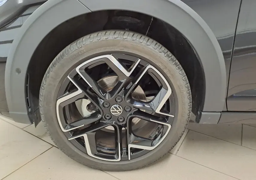 Gros plan sur la roue avant droite avec jante alliage noir et argent du Volkswagen Taigo Noir Intense nacré.