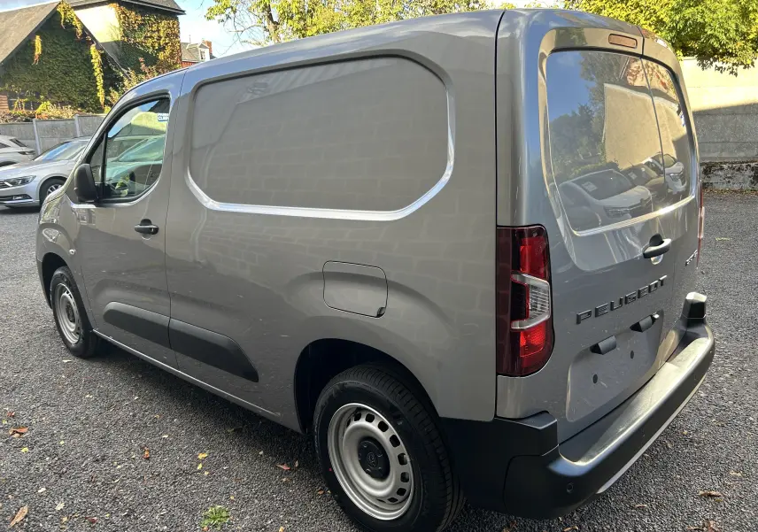 Vue 3/4 arrière droite d’un Peugeot Partner Fourgon gris acier avec portes arrière pleines et jantes acier noires.