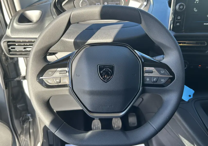 Vue rapprochée du volant multifonction noir du Peugeot Partner Fourgon 2026 avec tableau de bord et commandes visibles.