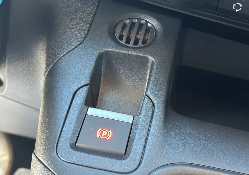 Bouton de frein de parking électronique éclairé en rouge sur la console centrale du Peugeot Partner Fourgon gris acier.