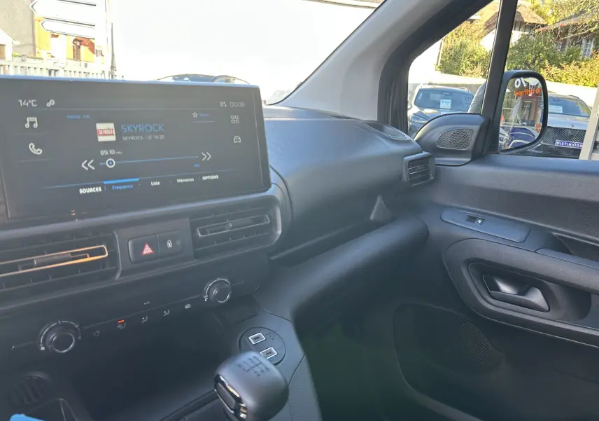 Intérieur du Peugeot Partner Fourgon 2026 vu côté passager, tableau de bord noir avec écran tactile et levier de vitesses.