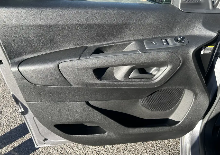 Vue rapprochée de la porte avant gauche du Peugeot Partner Fourgon gris acier, avec commandes électriques et haut-parleur intégré.