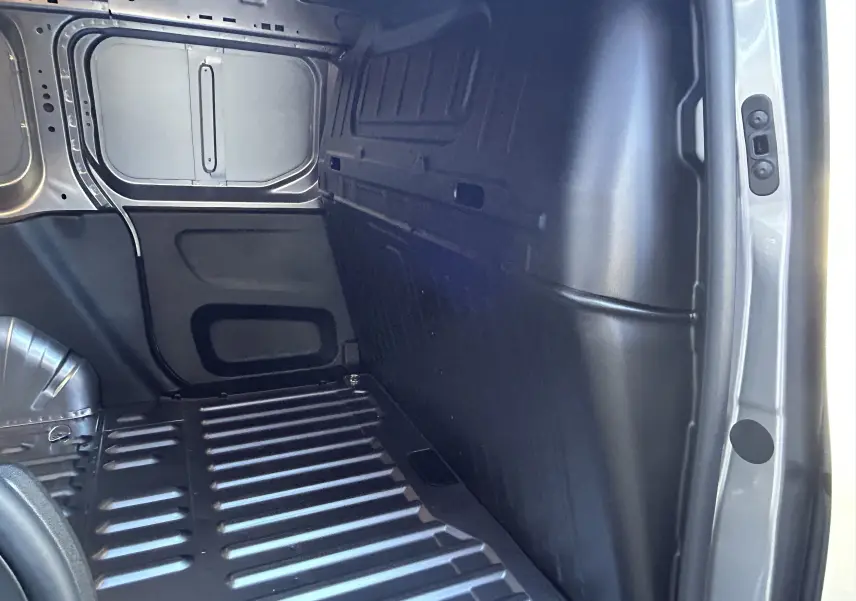 Intérieur du coffre côté droit du Peugeot Partner Fourgon gris acier, montrant la paroi et le plancher métallique.