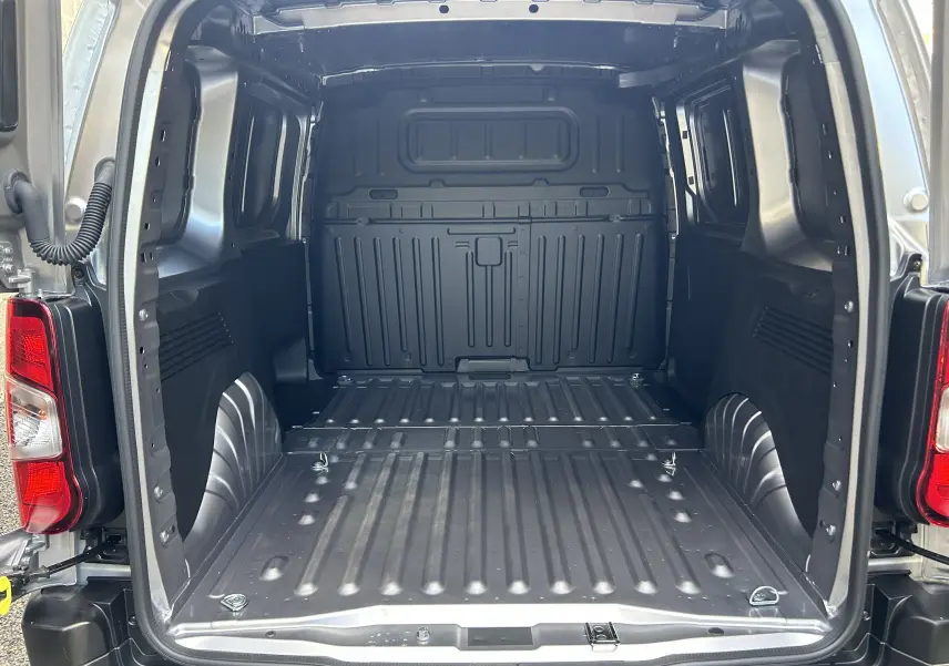 Vue arrière ouverte du fourgon Peugeot Partner III Ph.2 gris acier, montrant l’espace de chargement vide et métallique.