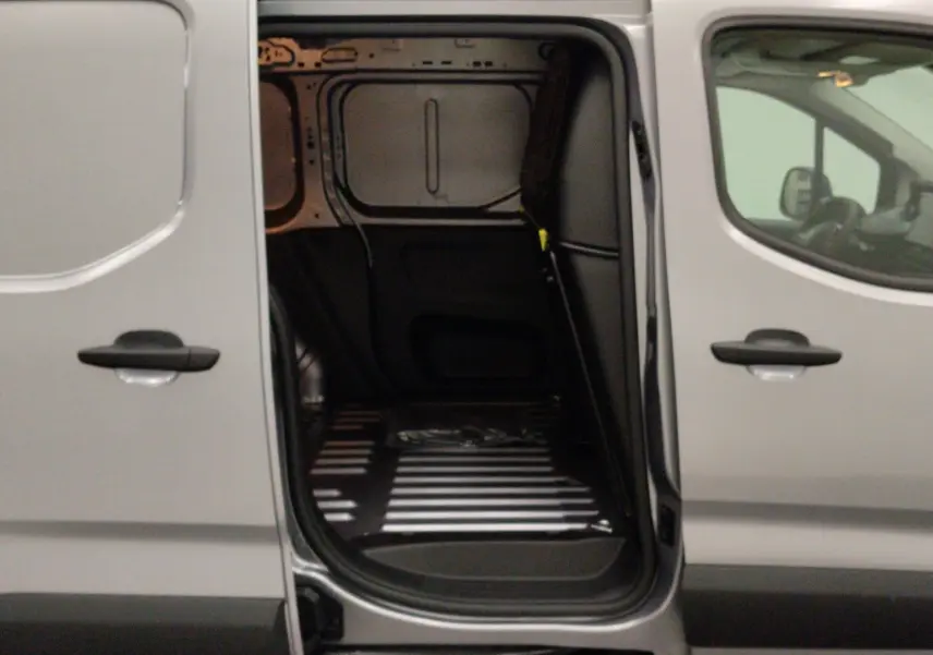 Vue latérale droite du Peugeot Partner Fourgon gris acier avec porte coulissante ouverte sur l’espace de chargement vide.
