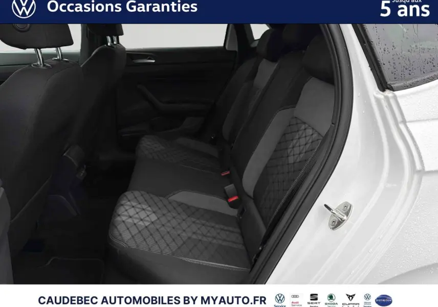 Vue intérieure côté arrière droit de la Volkswagen Polo blanche 2025, montrant les sièges arrière en tissu gris à motifs géométriques.