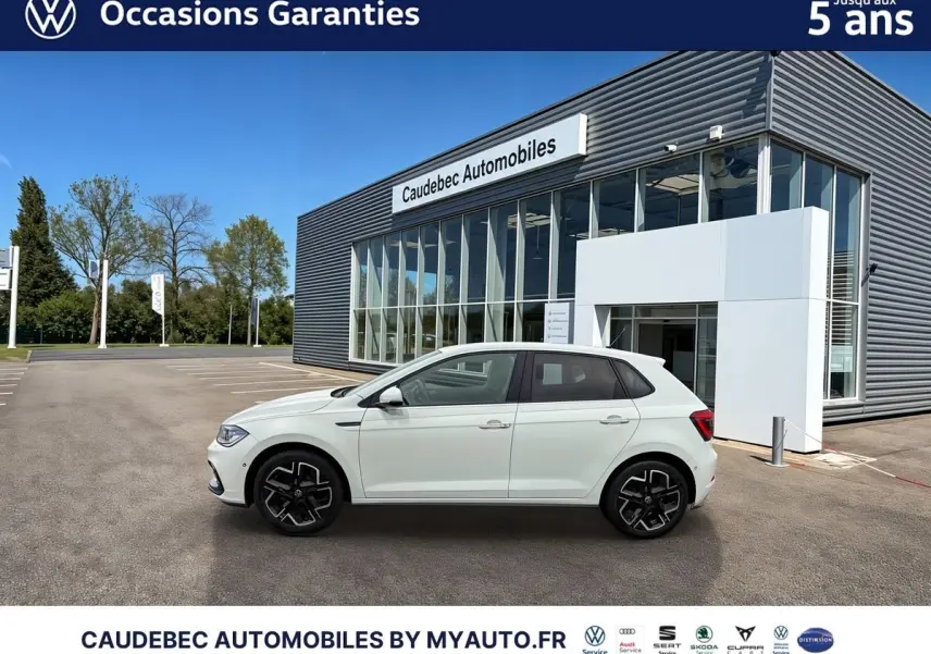 Profil côté gauche d'une Volkswagen Polo blanche 2025 avec jantes alliage 17 pouces, devant un bâtiment de concession.