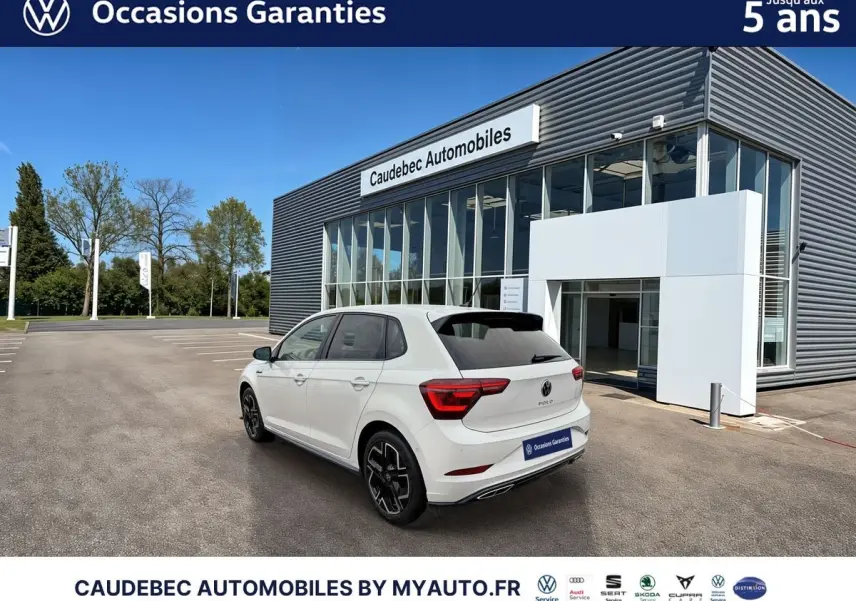Volkswagen Polo blanche vue en 3/4 arrière droit devant un bâtiment moderne de concession.