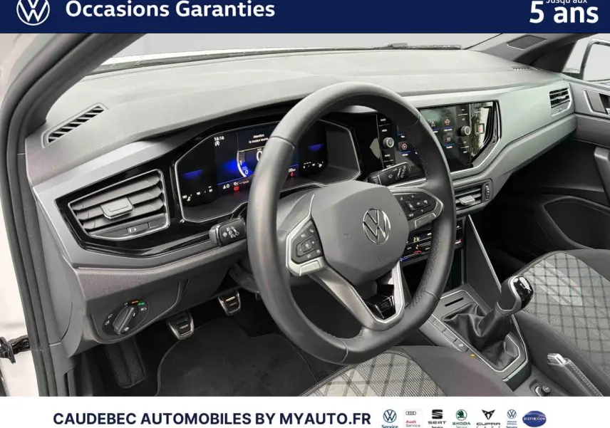 Vue intérieure côté conducteur de la Volkswagen Polo blanche 2025, volant cuir et tableau de bord digital.