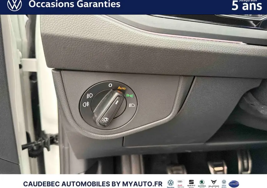 Détail du bouton de commande des feux sur le tableau de bord côté gauche d'une Volkswagen Polo blanche.