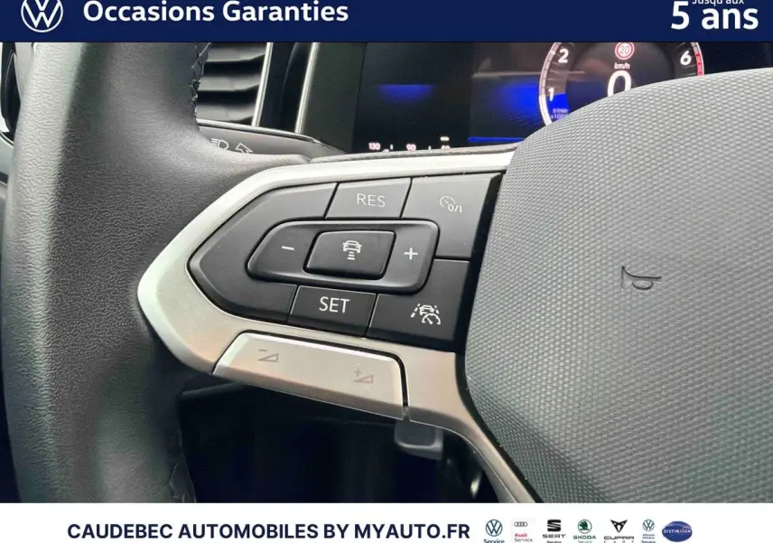 Gros plan sur les commandes à gauche du volant cuir de la Volkswagen Polo blanche, affichage digital en arrière-plan.