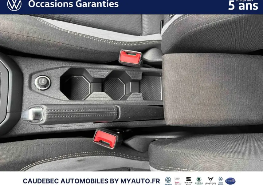 Vue plongeante sur la console centrale noire de la Volkswagen Polo 2025 avec frein à main manuel et accoudoir tissu.