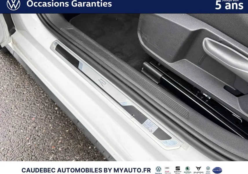 Gros plan sur le seuil de porte côté conducteur blanc de la Volkswagen Polo 2025 avec logo R-Line visible.