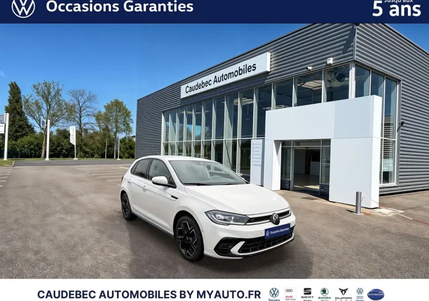 Vue 3/4 avant droite d'une Volkswagen Polo blanche 2025 avec jantes alliage noires devant un concessionnaire moderne.