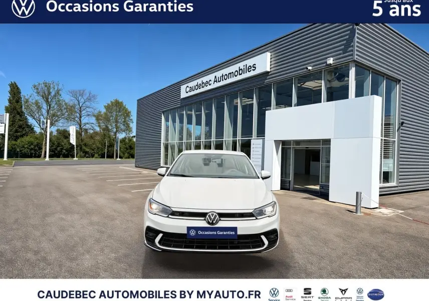 Volkswagen Polo blanche vue de face, avec calandre R-Line et feux LED, devant un bâtiment de concession.