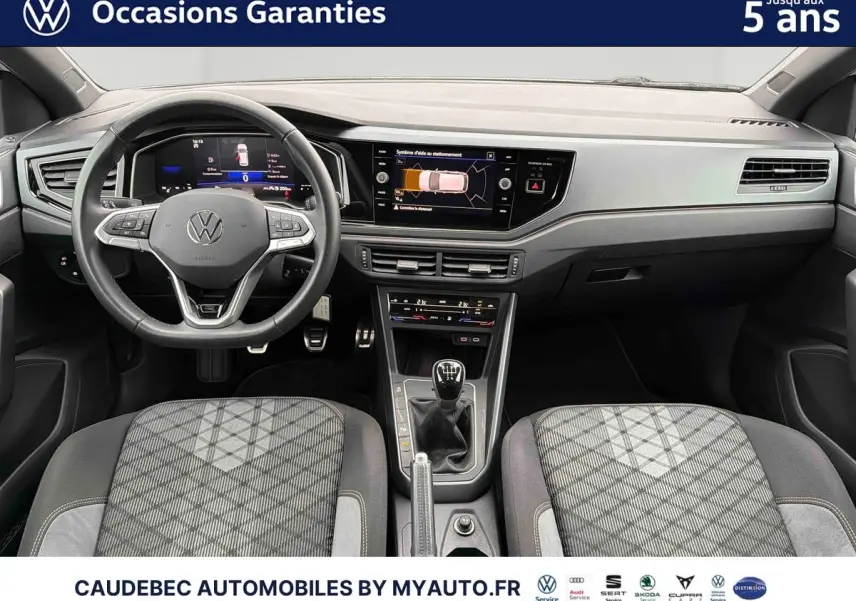 Vue intérieure avant de la Volkswagen Polo blanche 2025, volant cuir, boîte manuelle et écran tactile central.