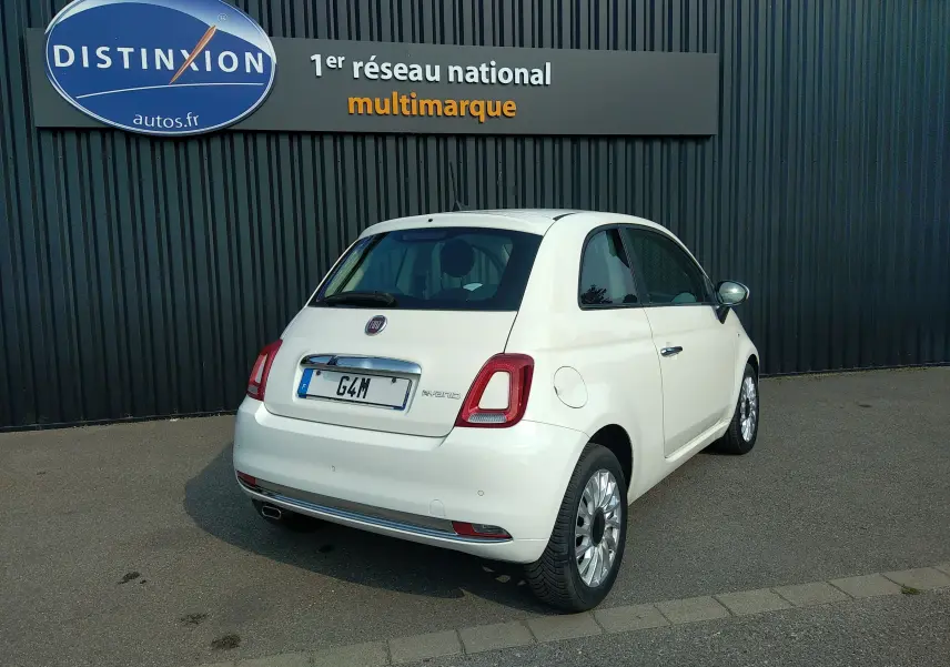 Vue 3/4 arrière droite d'une FIAT 500 blanche hybride 2021, avec jantes alliage et logo distinctif sur le hayon.