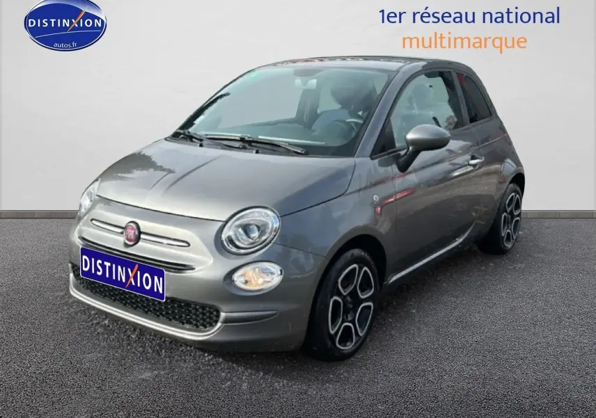 Fiat 500 gris vue 3/4 avant droit avec jantes originales et phares ronds allumés sur fond neutre.