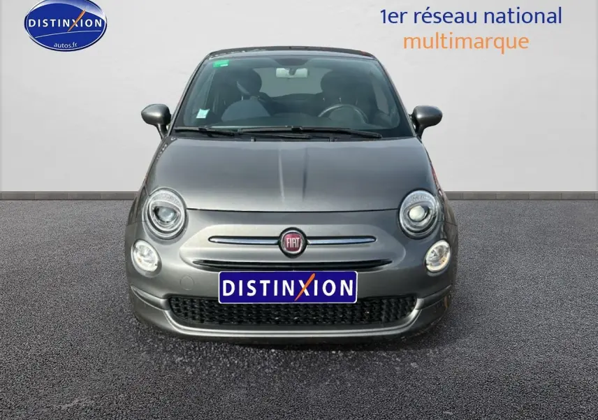 Vue frontale d'une Fiat 500 gris métallisé 2022 avec phares ronds allumés et logo FIAT visible.