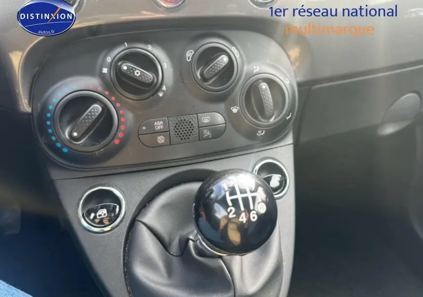 Le levier de vitesses manuel noir et la console centrale avec commandes de climatisation d'une Fiat 500 grise.