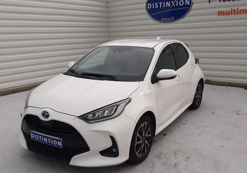 Toyota Yaris 1.5 Hybrid blanc vue 3/4 avant droit, avec jantes alliage et calandre noire distinctive.