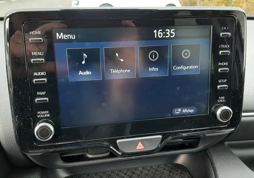Écran tactile central de la Toyota Yaris 2023 affichant le menu principal avec options audio, téléphone, infos et configuration.