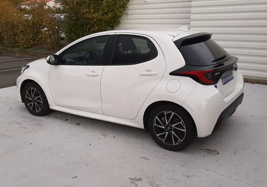 Toyota Yaris blanche vue de profil côté gauche, avec jantes alliage noires et vitres arrière teintées.