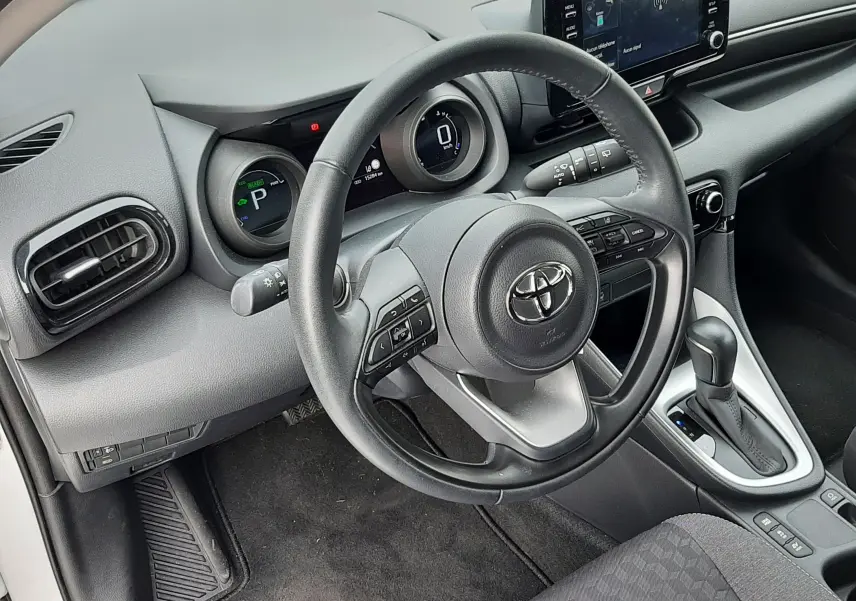 Vue intérieure côté conducteur de la Toyota Yaris 1.5 Hybrid 2023 avec tableau de bord numérique et volant multifonction noir.