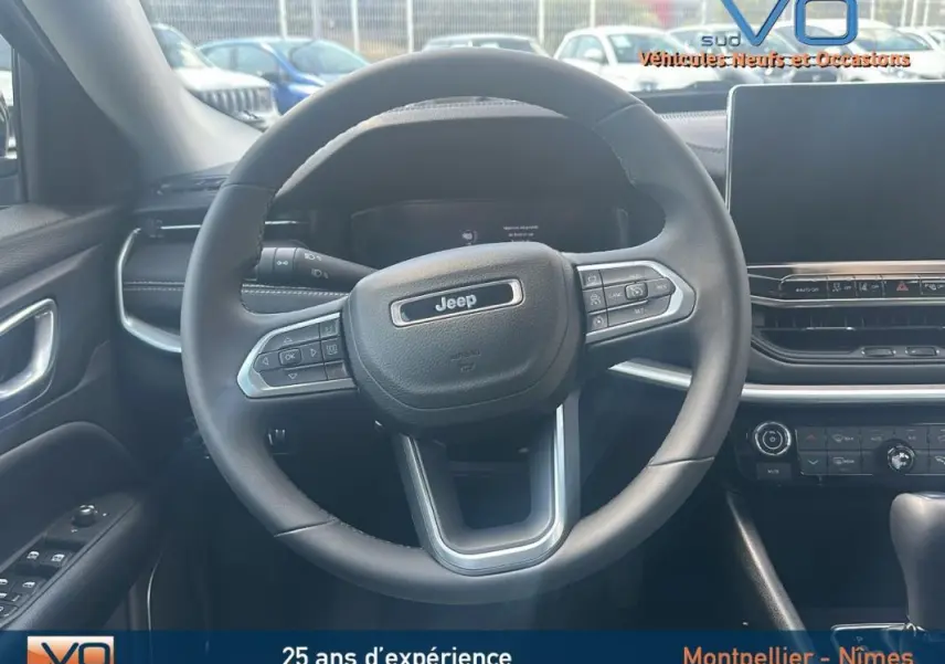 Vue intérieure centrée sur le volant Jeep du Compass 2024 avec tableau de bord et écran tactile visibles.