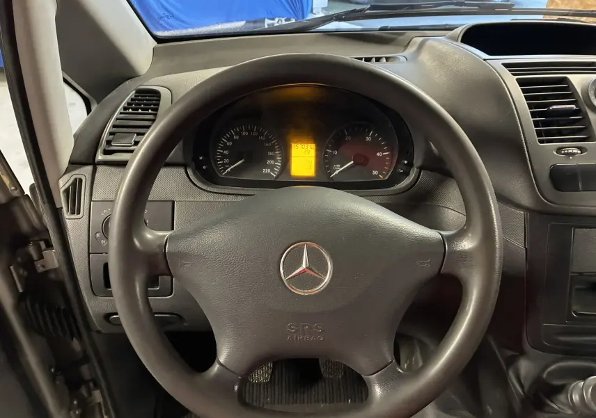 Vue intérieure centrée sur le volant noir et le tableau de bord du Mercedes Vito 2.8 113 CDI fourgon long gris de 2012.