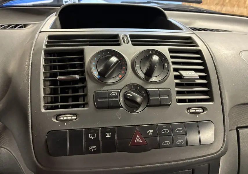 Vue rapprochée du tableau de bord gris du Mercedes Vito 2.8 113 CDI, montrant les commandes de climatisation et ventilation.