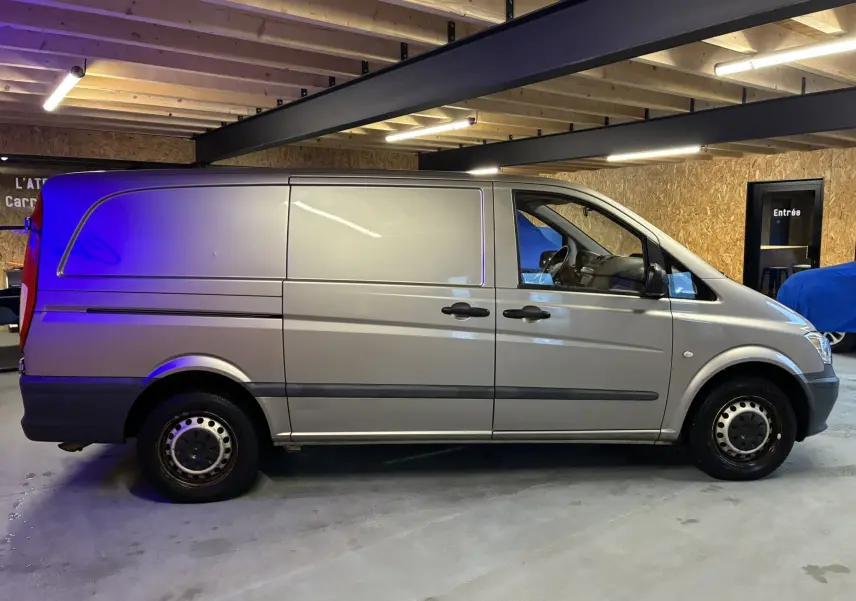 Vue de profil côté gauche d’un Mercedes Vito gris 2.8 113 CDI fourgon long, stationné en intérieur sous plafond en bois.
