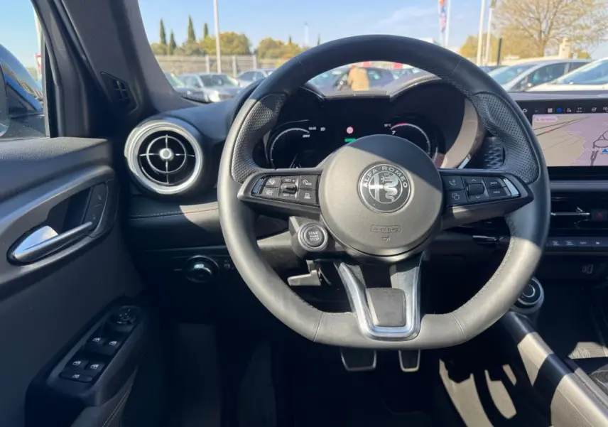 Intérieur de l'Alfa Romeo Tonale 2025, vue centrée sur le volant cuir noir avec logo Alfa Romeo et tableau de bord digital.