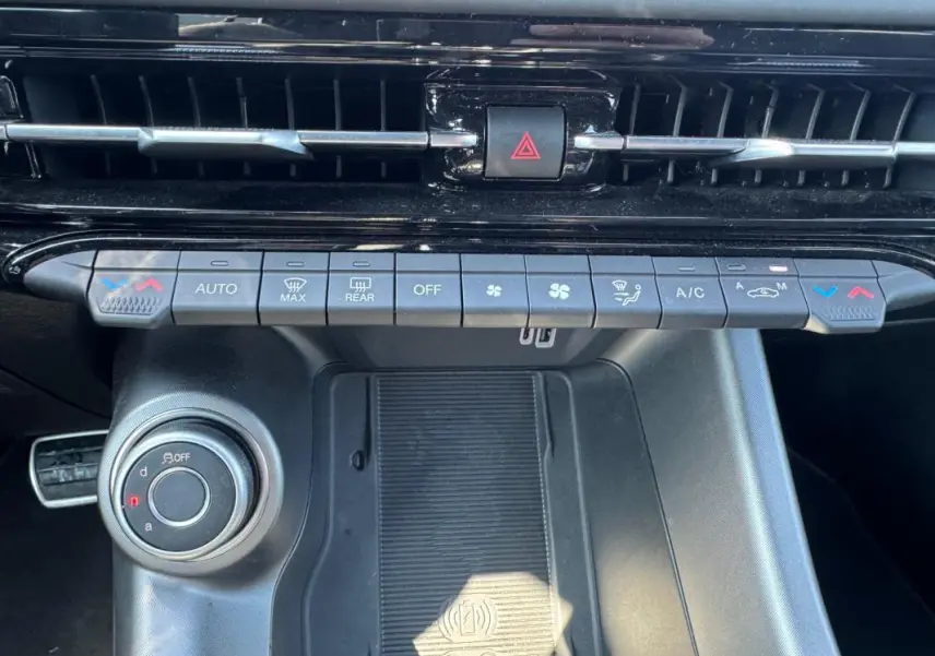 Vue rapprochée de la console centrale de l'Alfa Romeo Tonale 2025, avec commandes climatisation et molette de sélection de mode de conduite.