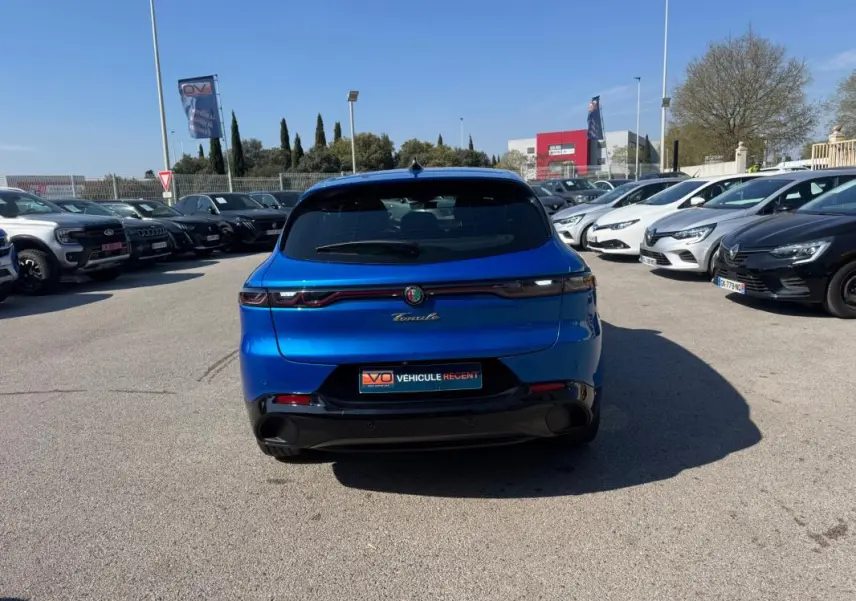 Vue arrière d'une Alfa Romeo Tonale Sprint 2025 bleu foncé avec feux arrière reliés par un bandeau lumineux rouge.