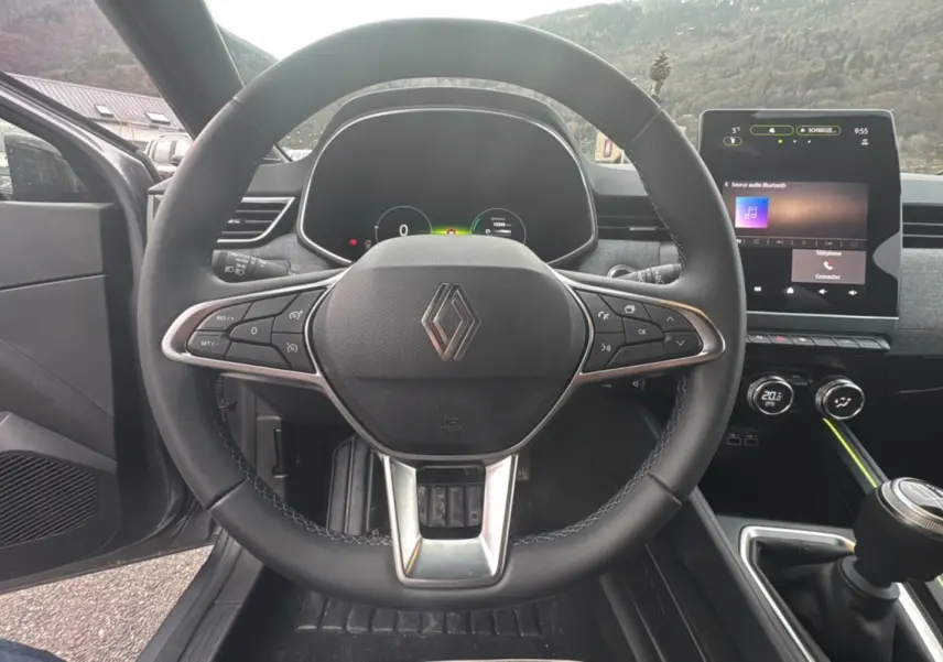 Vue intérieure centrée sur le volant cuir multifonctions et l’écran tactile du tableau de bord de la Renault Clio 2025.