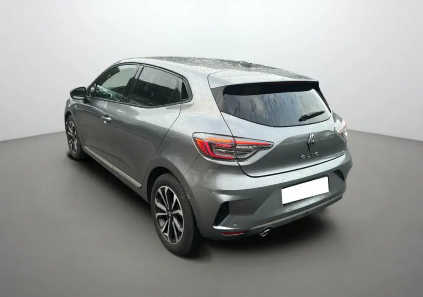 Vue 3/4 arrière droite d'une Renault Clio gris schiste 2025 avec jantes alu noires et vitres surteintées.