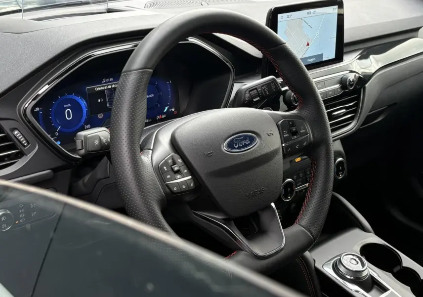 Vue intérieure centrée sur le volant ST-Line noir avec surpiqûres rouges et écran tactile du Ford Kuga 2023.