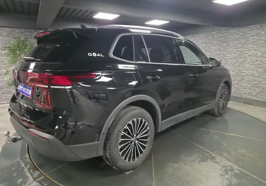 Volkswagen Tiguan noir en 3/4 arrière droit, avec jantes alliage et crochet d'attelage visible.