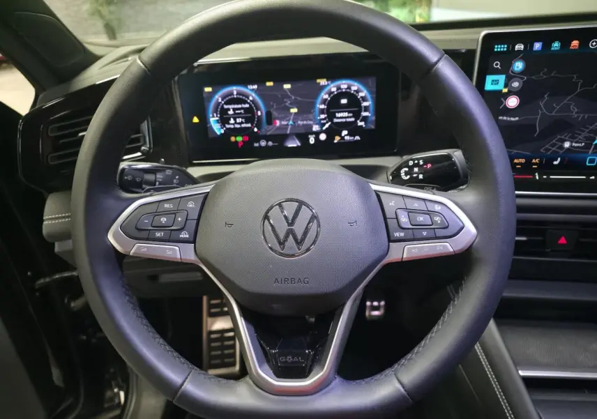 Vue intérieure centrée sur le volant cuir noir du Volkswagen Tiguan 2025 avec tableau de bord numérique et écran tactile.