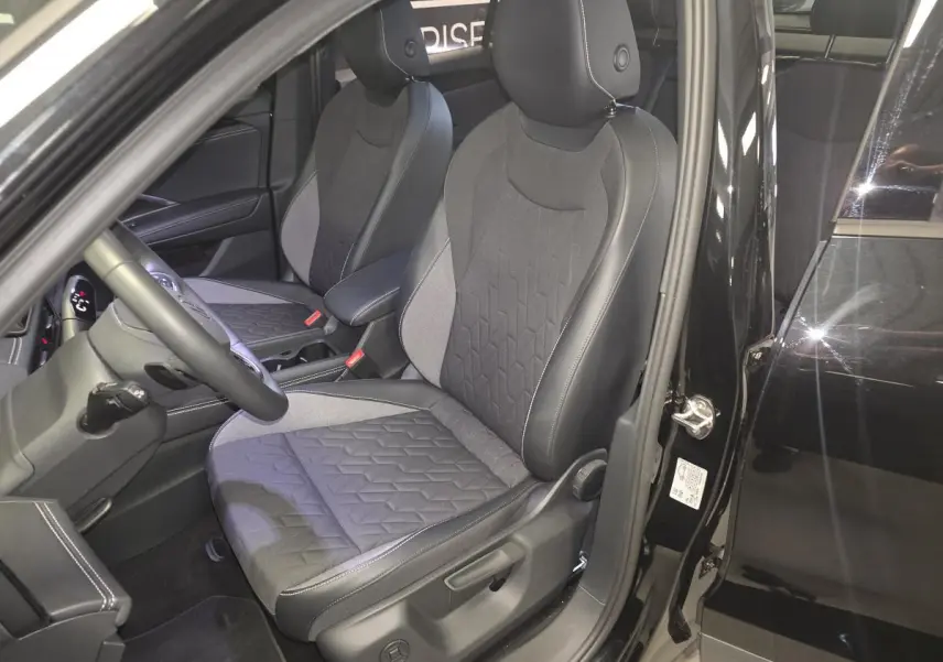Vue intérieure côté conducteur du Volkswagen Tiguan noir 2025, mettant en valeur les sièges avant en tissu et cuir.